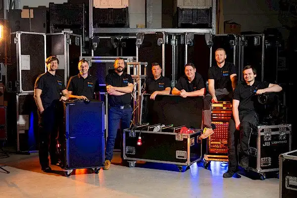 Eine Gruppe von Männern vor einem großen Raum voller Orange Veranstaltungstechnik in Landshut.