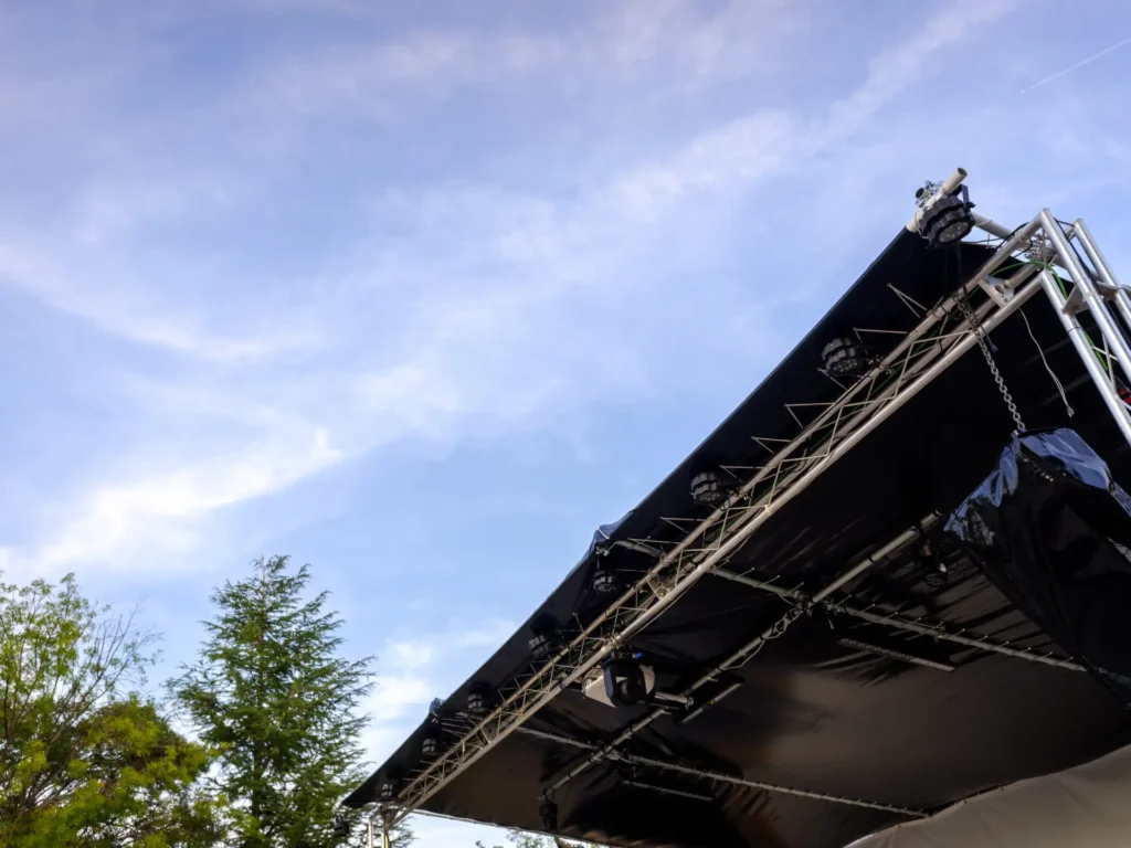Beleuchtete Open-Air-Bühnenkonstruktion mit Traversen und Scheinwerfern vor blauem Himmel – Veranstaltungstechnik im Einsatz in Pullach im Isartal