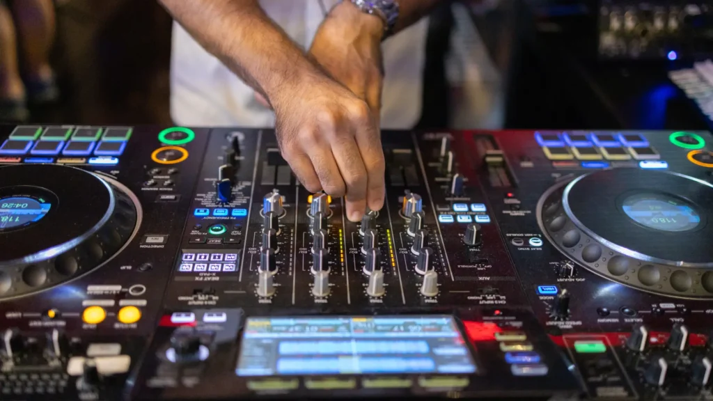 Nahaufnahme eines DJs, der die Regler an einem professionellen Pioneer DJ-Mischpult bedient